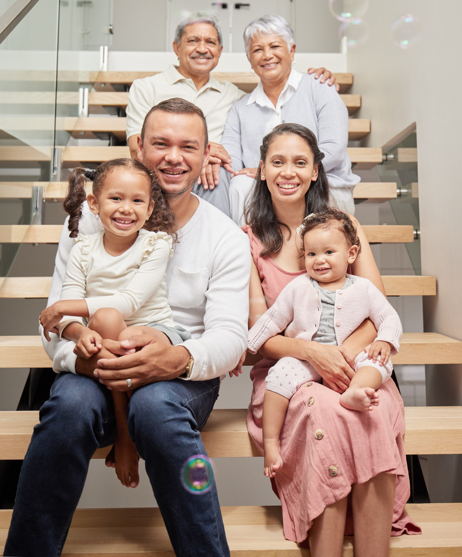 Portrait of a happy family posing for a picture on stairs in a house, smiling and relaxing together. Happy children bonding and enjoying time with their parents on a visit to their grandparents home